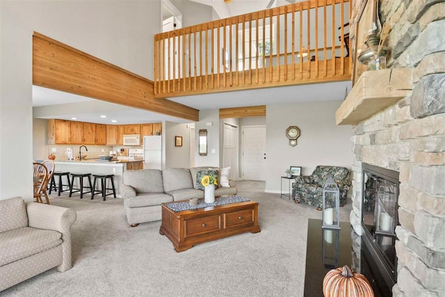 carpeted living room with sink, a fireplace, and a high ceiling