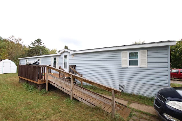 back of house featuring a deck, a lawn, and a shed