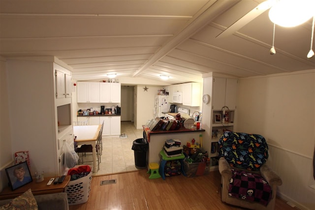 interior space featuring vaulted ceiling with beams and light hardwood / wood-style flooring