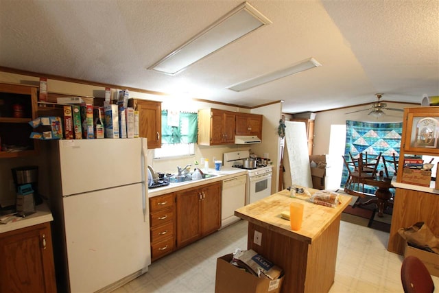 kitchen with white appliances, a textured ceiling, lofted ceiling, a center island, and sink