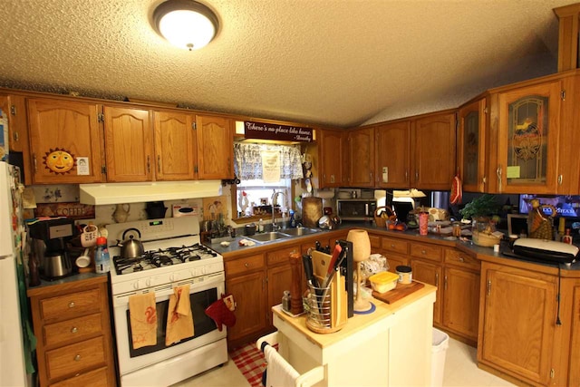 kitchen with a textured ceiling, white appliances, and sink