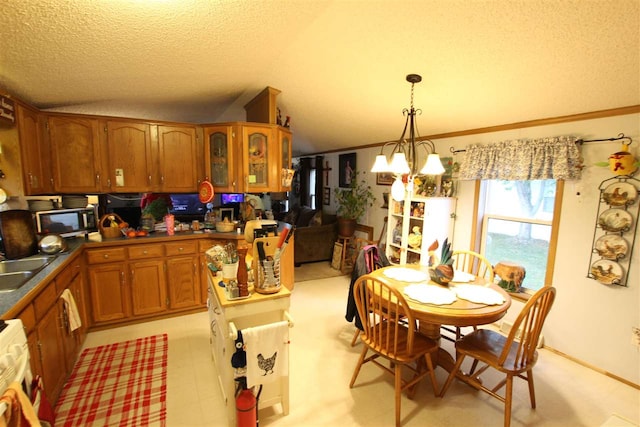 kitchen featuring an inviting chandelier, lofted ceiling, a textured ceiling, and hanging light fixtures