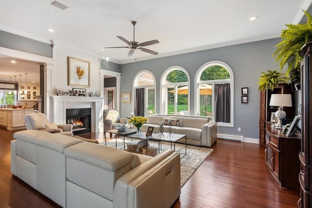 290 Mitchell Hills Dr, Petoskey, MI 49770 - living room with a ceiling fan, baseboard heating, decorative columns, a warm lit fireplace, and dark wood-style flooring