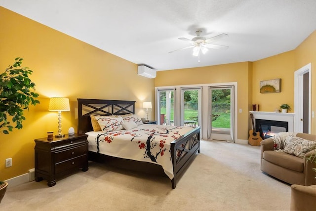 290 Mitchell Hills Dr, Petoskey, MI 49770 - carpeted bedroom featuring access to exterior, a wall unit AC, a glass covered fireplace, baseboards, and a ceiling fan