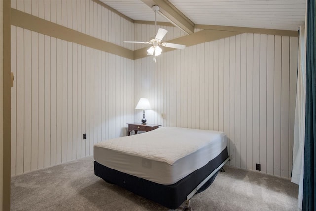 carpeted bedroom with wooden walls, lofted ceiling with beams, and ceiling fan