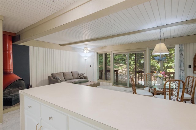 kitchen with ceiling fan, white cabinets, beamed ceiling, decorative light fixtures, and light colored carpet