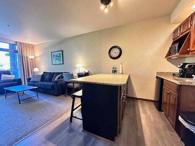 kitchen featuring sink, kitchen peninsula, dark wood-type flooring, black appliances, and a kitchen breakfast bar