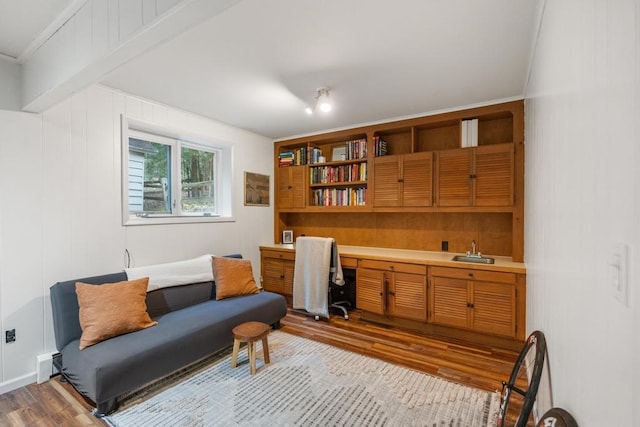 sitting room with indoor wet bar, light wood-type flooring, built in desk, and crown molding