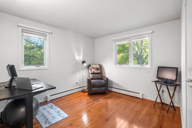 office space featuring plenty of natural light, hardwood / wood-style floors, and a baseboard heating unit