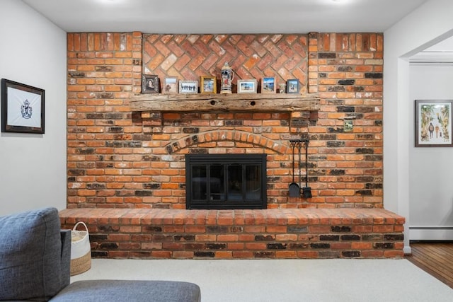 room details with hardwood / wood-style flooring, a fireplace, and a baseboard radiator