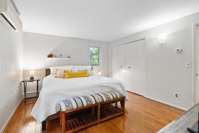 bedroom featuring light hardwood / wood-style floors, a closet, and a wall mounted AC