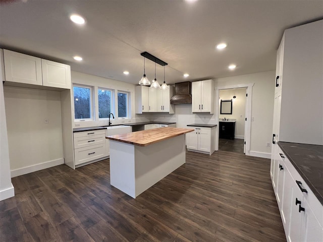 kitchen with pendant lighting, a center island, premium range hood, and white cabinetry