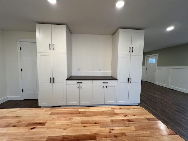 bar with white cabinets and hardwood / wood-style flooring