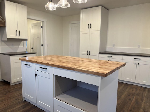 kitchen with butcher block counters, hanging light fixtures, dark hardwood / wood-style floors, a kitchen island, and white cabinetry