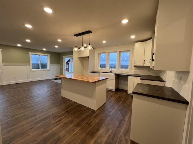 kitchen with a center island, sink, dark hardwood / wood-style flooring, pendant lighting, and white cabinets