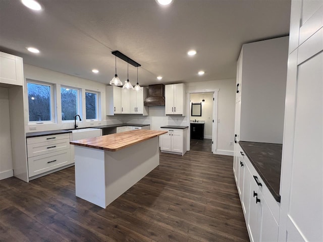 kitchen with a center island, white cabinetry, and premium range hood