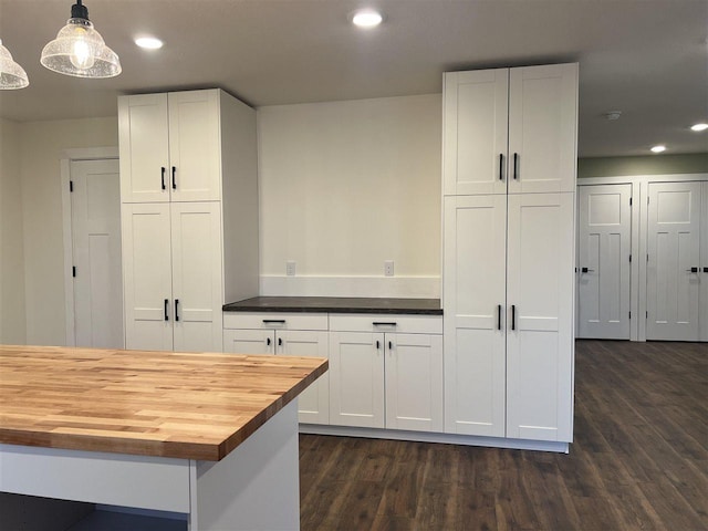 kitchen featuring wooden counters, decorative light fixtures, and white cabinets