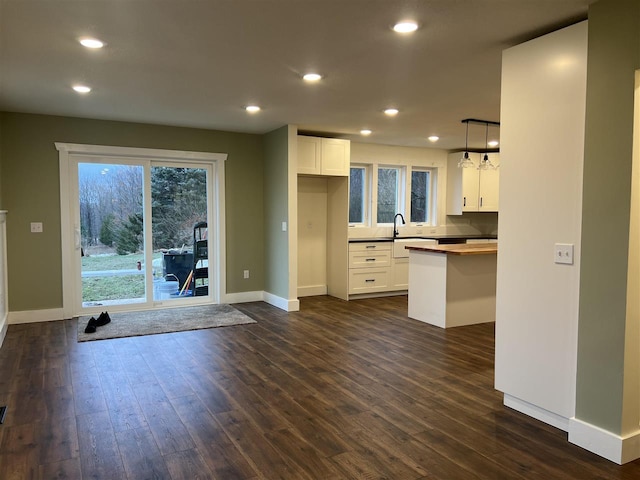 kitchen featuring white cabinets, hanging light fixtures, and dark wood-type flooring