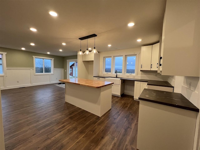 kitchen featuring dark hardwood / wood-style flooring, white cabinetry, a center island, and pendant lighting