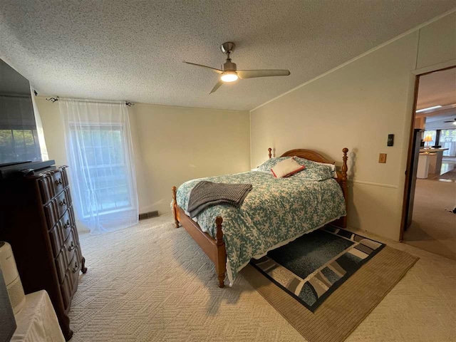 bedroom featuring ceiling fan, light carpet, and a textured ceiling