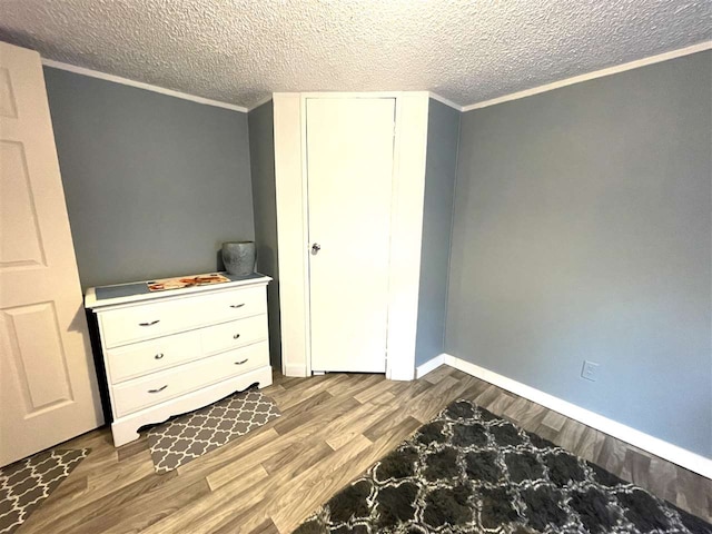 unfurnished bedroom with wood-type flooring, a textured ceiling, and ornamental molding