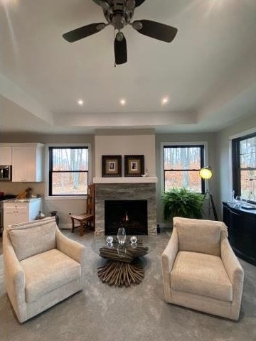 living room with ceiling fan, a raised ceiling, and a wealth of natural light