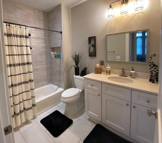 full bathroom with vanity, shower / bathtub combination with curtain, toilet, and tile patterned floors