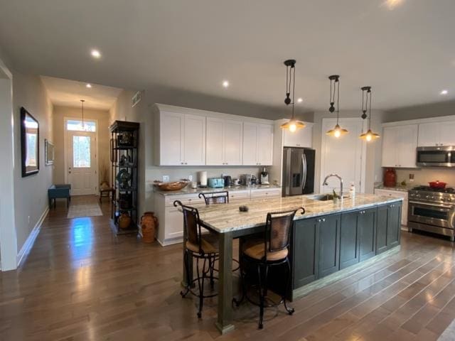 kitchen with a large island, white cabinets, hanging light fixtures, dark hardwood / wood-style flooring, and appliances with stainless steel finishes