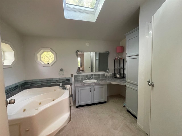 bathroom with a skylight, a bathing tub, a healthy amount of sunlight, and vanity