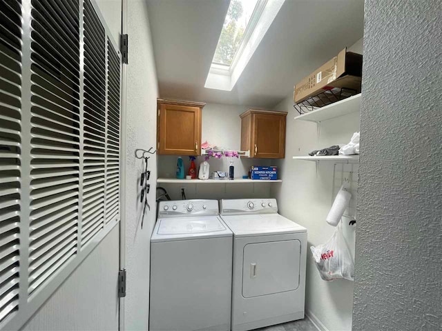 washroom featuring a skylight, cabinets, and washing machine and clothes dryer