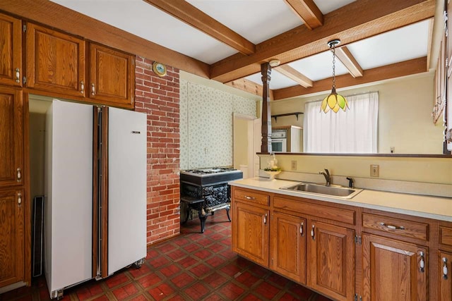 kitchen with pendant lighting, beamed ceiling, white fridge, and sink