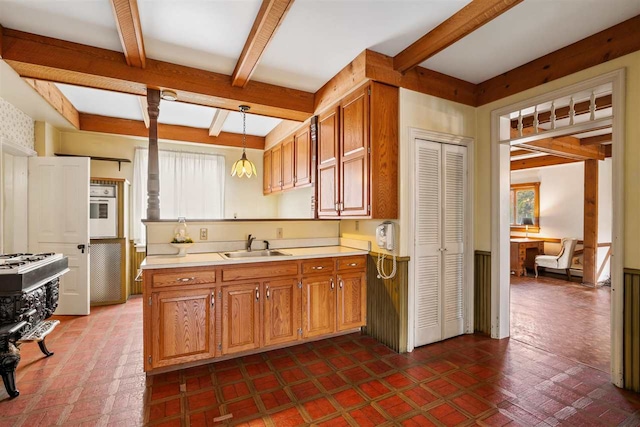 kitchen featuring beamed ceiling, decorative light fixtures, white oven, and sink