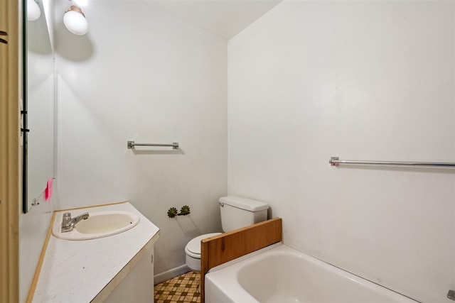 bathroom with a washtub, vanity, and toilet