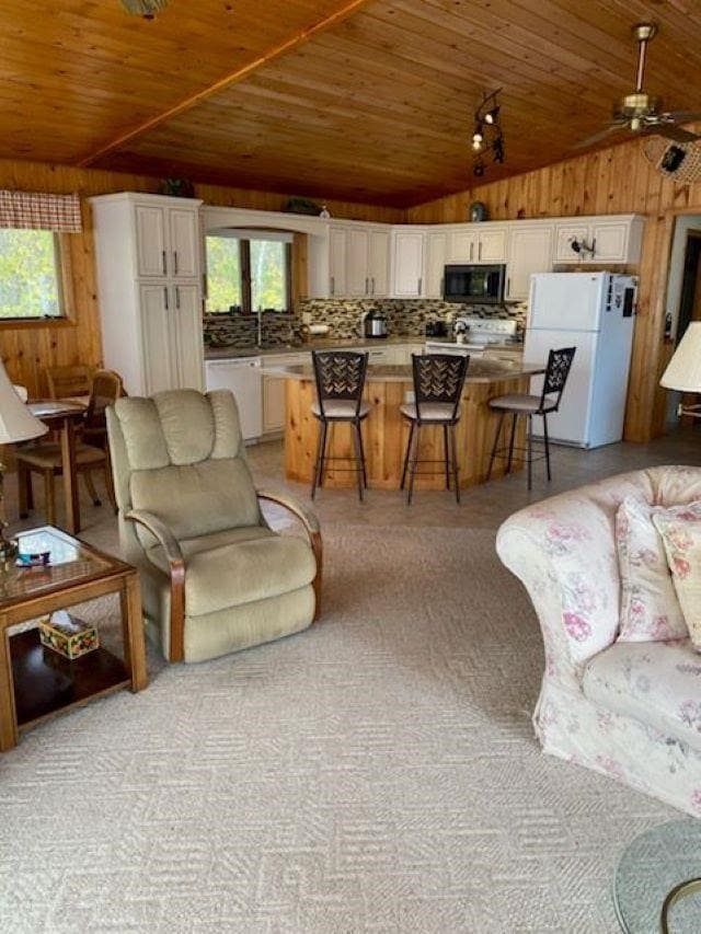 living room featuring wood walls, ceiling fan, wooden ceiling, and vaulted ceiling