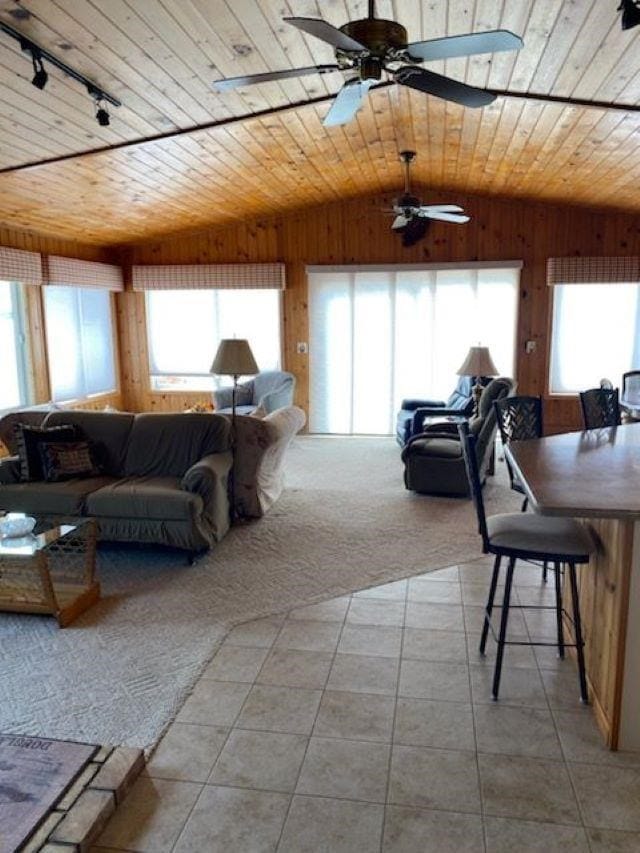 carpeted living room with wood ceiling, wood walls, vaulted ceiling, and plenty of natural light