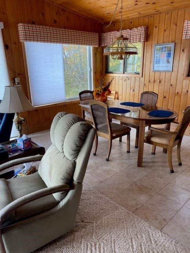 dining space with wood walls, wood ceiling, light tile patterned floors, and plenty of natural light