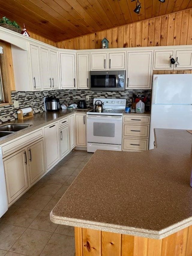 kitchen featuring white appliances, sink, wooden ceiling, vaulted ceiling, and light tile patterned floors