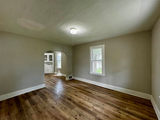 spare room with dark hardwood / wood-style floors and a textured ceiling