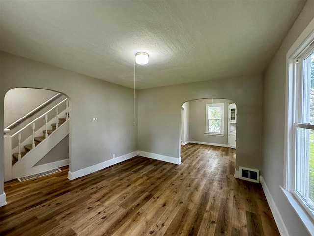 unfurnished room featuring plenty of natural light, dark hardwood / wood-style flooring, and a textured ceiling