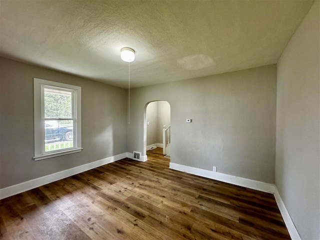 unfurnished room featuring wood-type flooring and a textured ceiling