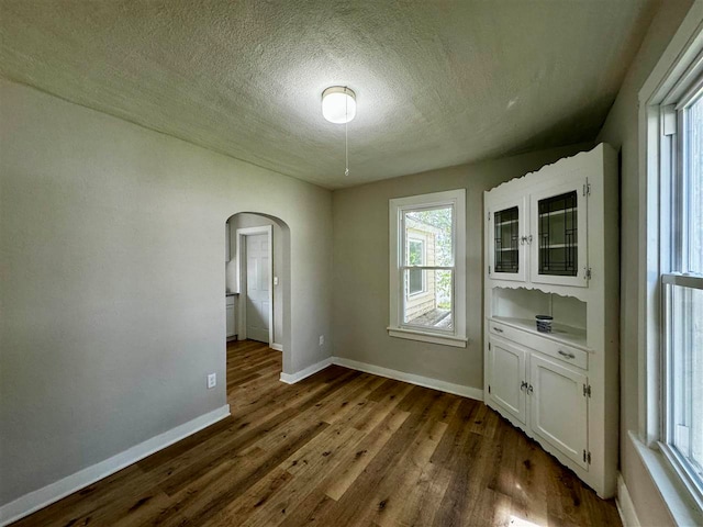 empty room featuring a textured ceiling and dark hardwood / wood-style floors