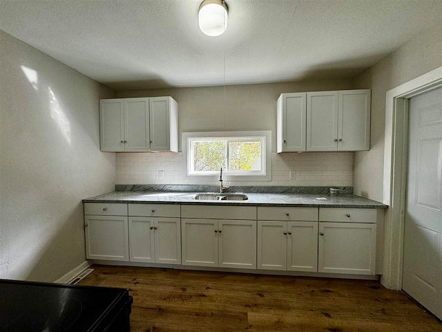 kitchen with white cabinets, dark hardwood / wood-style floors, sink, and decorative backsplash