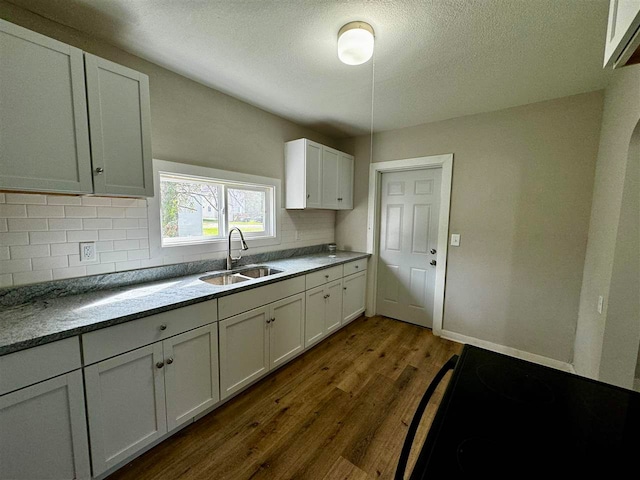 kitchen featuring sink, a textured ceiling, backsplash, dark wood-type flooring, and white cabinetry