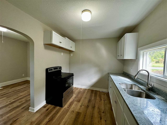 kitchen with sink, stainless steel range with electric stovetop, a textured ceiling, white cabinetry, and dark hardwood / wood-style floors