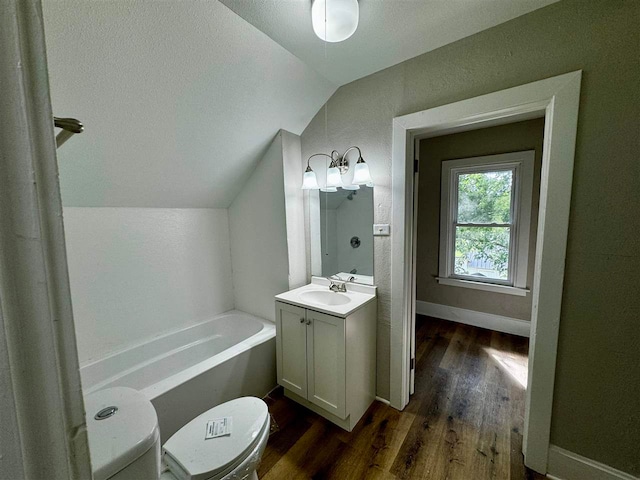 bathroom with vanity, toilet, wood-type flooring, a tub to relax in, and vaulted ceiling