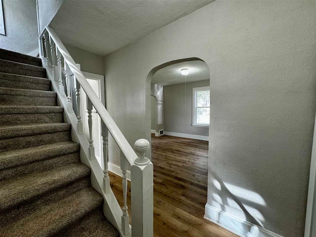 staircase featuring hardwood / wood-style floors and a textured ceiling