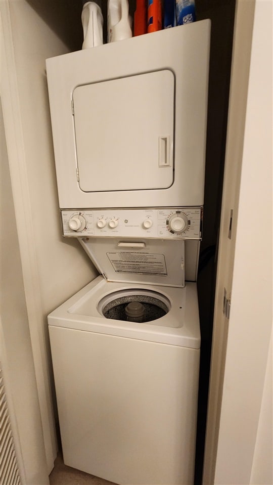 clothes washing area featuring stacked washer and clothes dryer