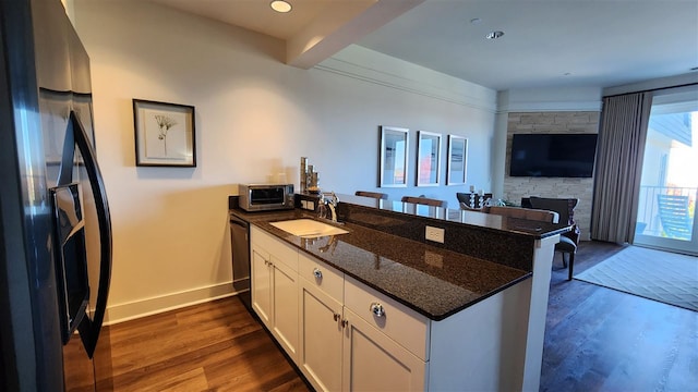 kitchen with sink, appliances with stainless steel finishes, kitchen peninsula, and white cabinets