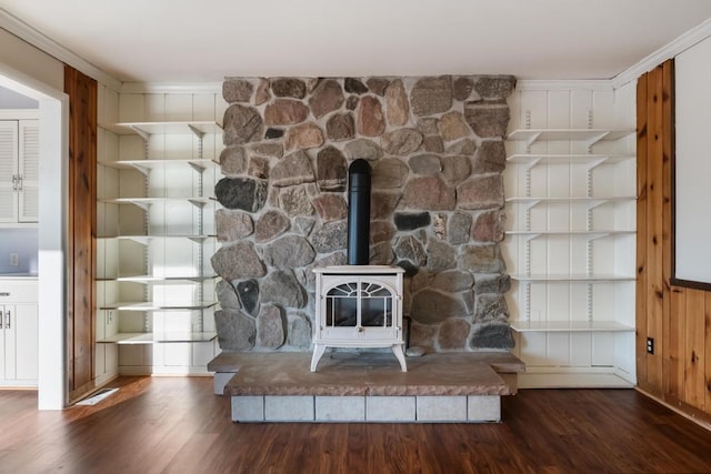 room details with a wood stove, hardwood / wood-style flooring, wooden walls, and crown molding