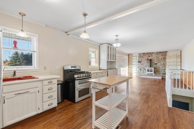 kitchen with range with two ovens, a wood stove, hanging light fixtures, white cabinetry, and hardwood / wood-style flooring